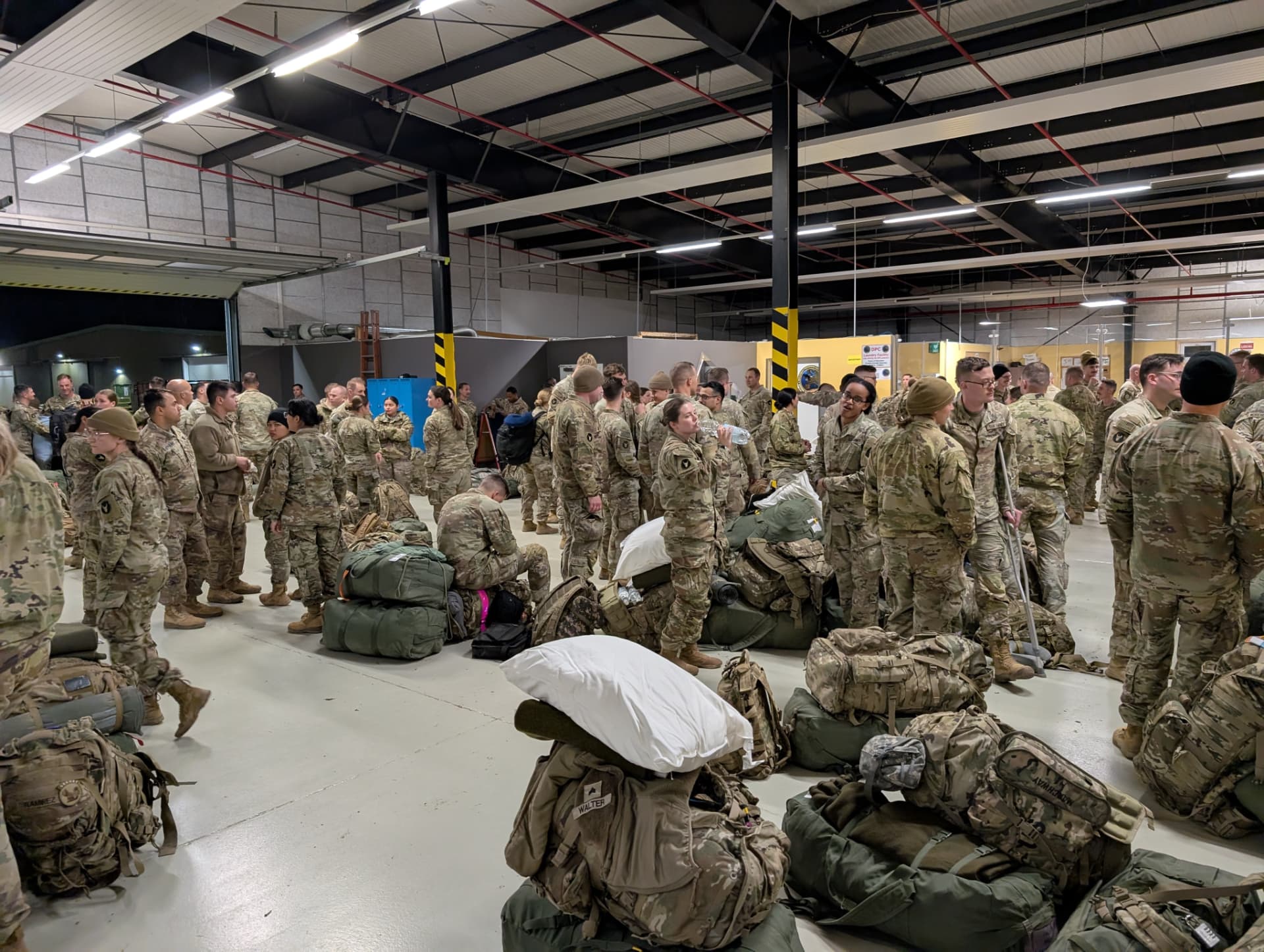 Soldiers and their gear filling a hangar during a deployment movement in Germany.