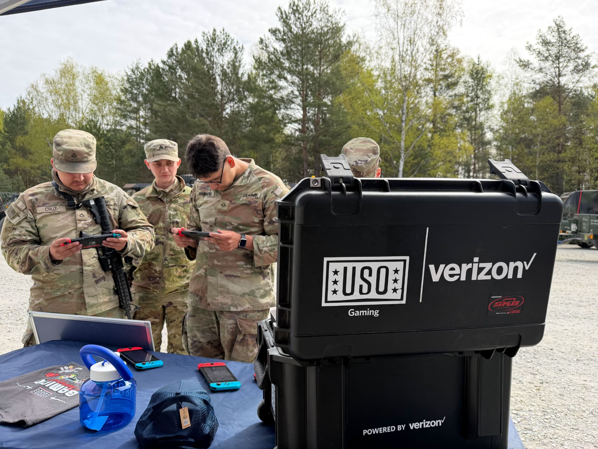 Soldiers playing handheld games beside a USO and Verizon mobile gaming kit.