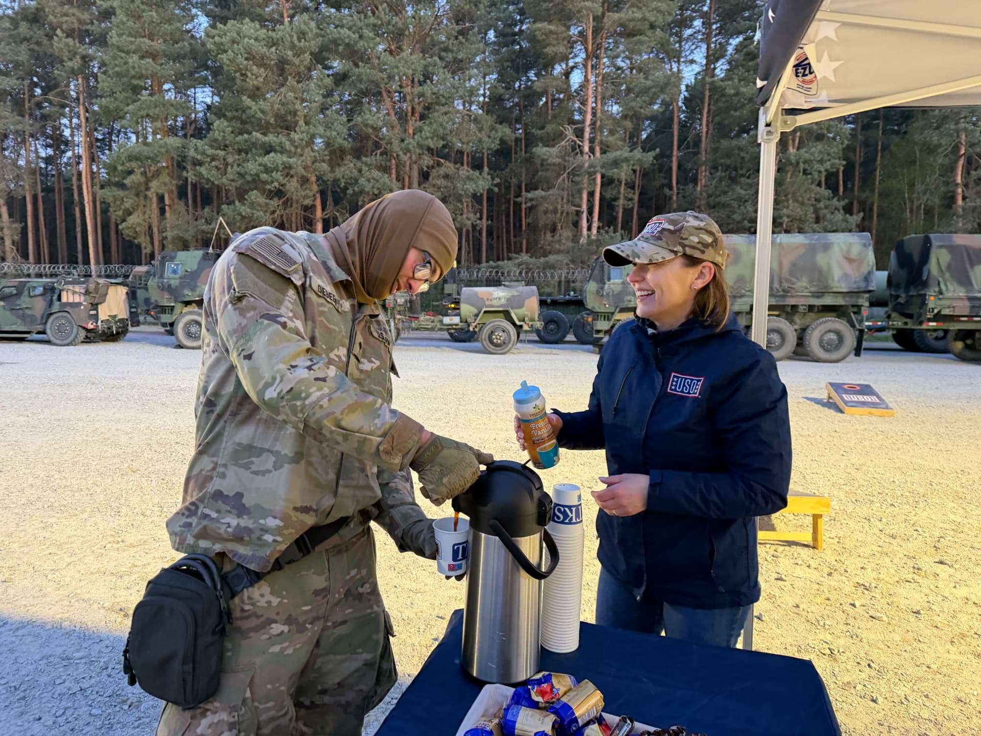 A USO staff member handing hot coffee to a soldier at a field service point in Germany.