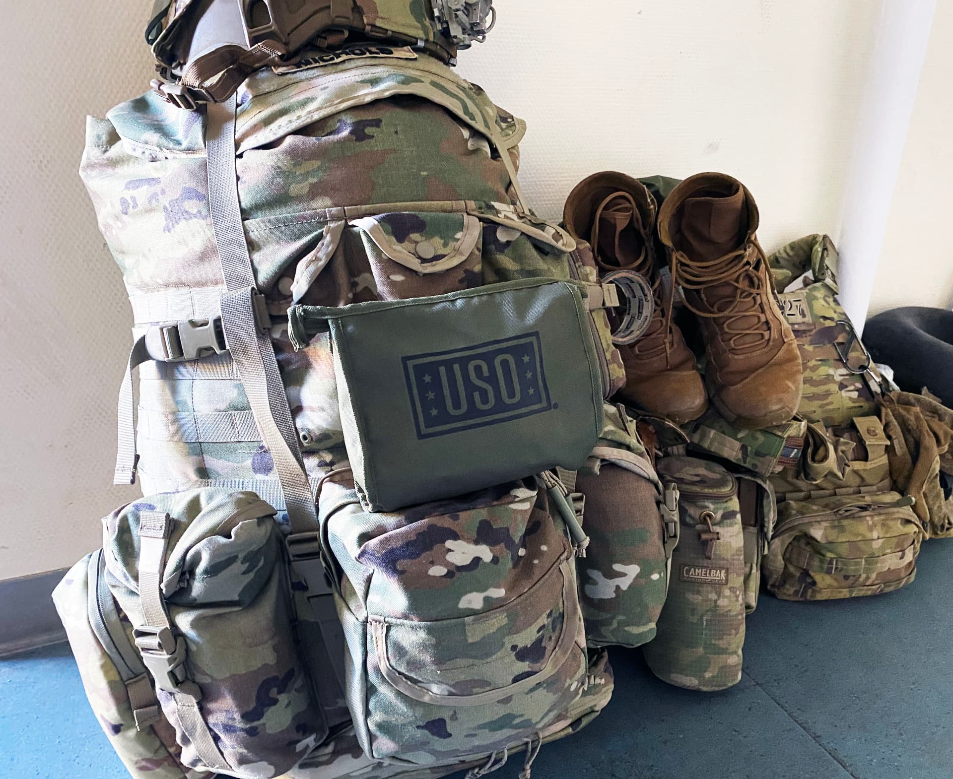 A USO care pack strapped to a soldier’s rucksack next to boots and field gear.